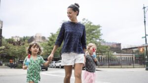 Girls eating ice creams while walking with mother on street