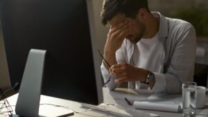 Exhausted businessman holding his head in pain while working on