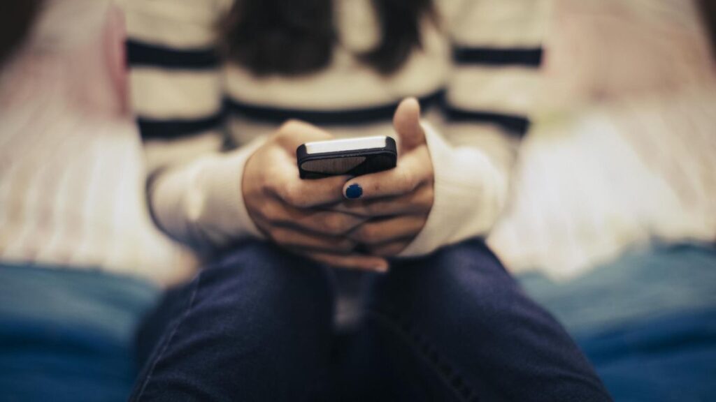 Close up of teenage girl in bedroom using smart phone