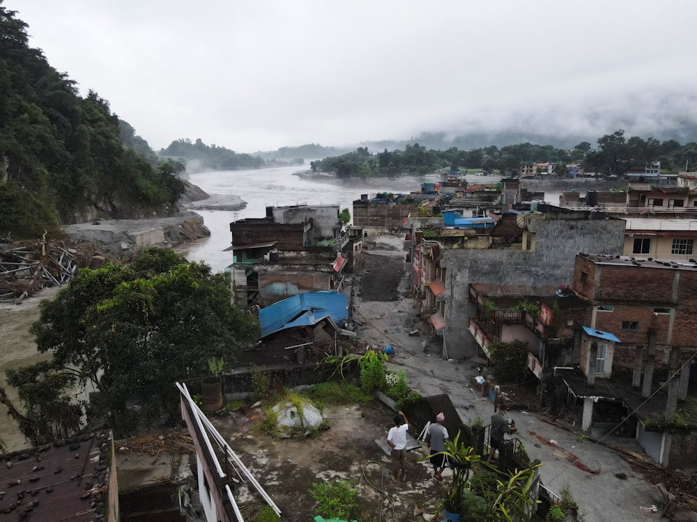 Drone view of people inspecting a damaged house after the deadly flash floods and mudslide, at Devighat