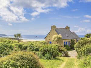 Altes Sommerhaus an der französischen Küste mit schöner Aussicht auf das Meer und einen üppigen grünen Garten an einem s