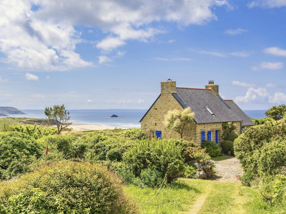 Altes Sommerhaus an der französischen Küste mit schöner Aussicht auf das Meer und einen üppigen grünen Garten an einem s
