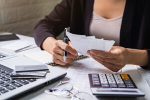 Stressed young woman checking bills, taxes, bank account balance and calculating expenses in the living room at home