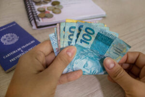 São Paulo, Brazil. March 30, 2021. Hand holding Brazilian money and work card.