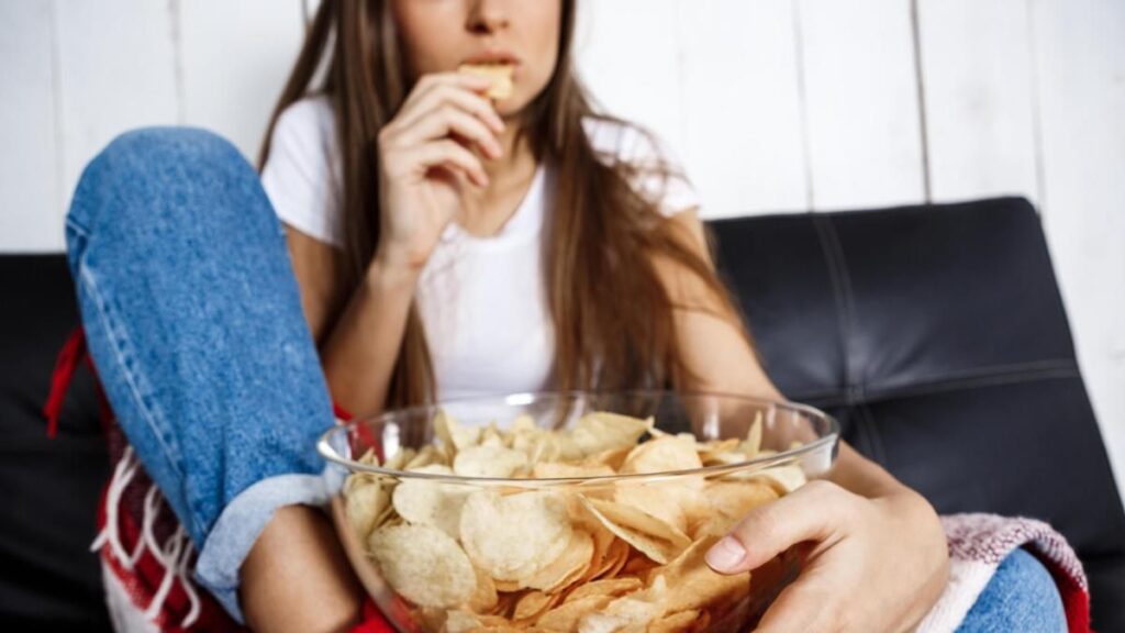 Young pretty girl watching tv, sitting on sofa at home.